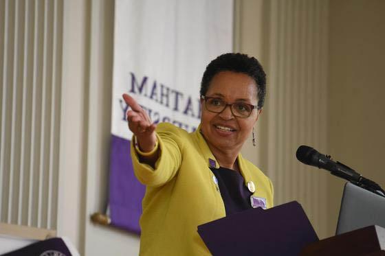 Photo of a woman speaking at a podium, gesturing to something off camera